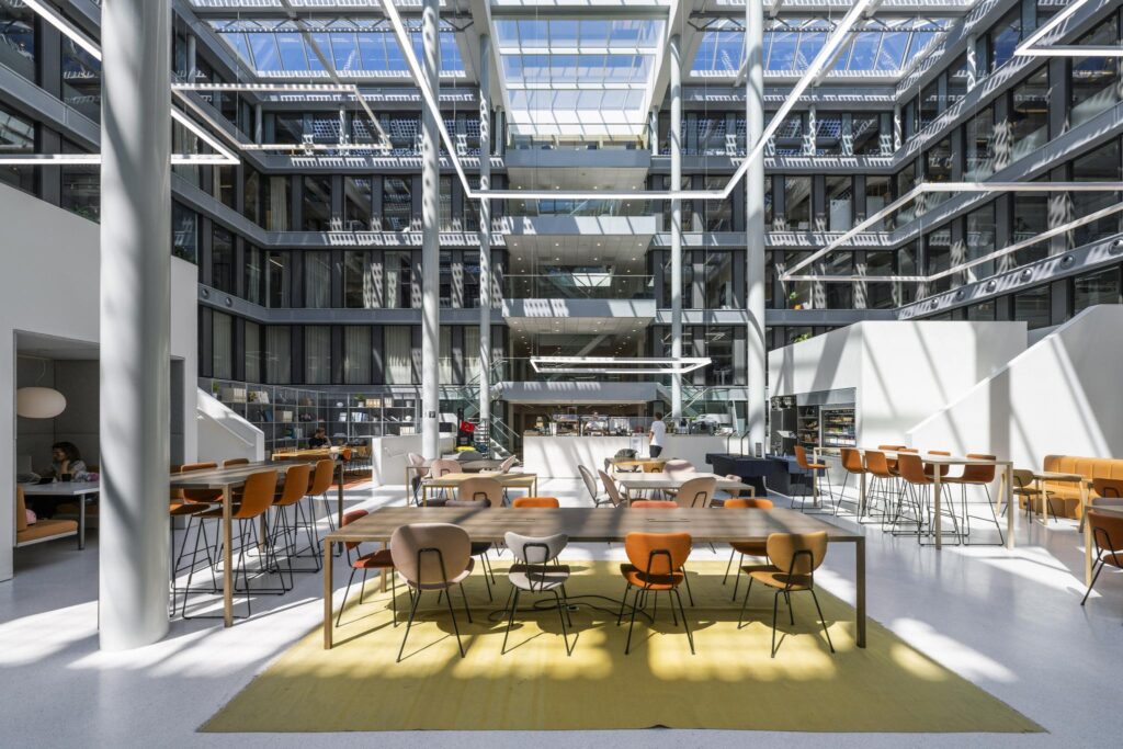 Modern atrium with high ceilings, large windows, and communal seating at Mr. Treublaan.